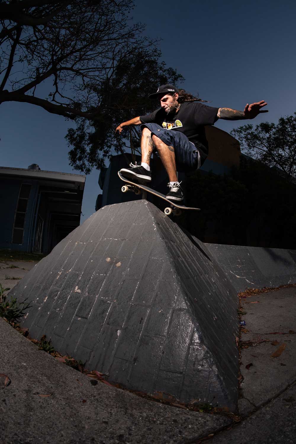 Skateboarder performing a trick on a concrete ledge with trees in the background